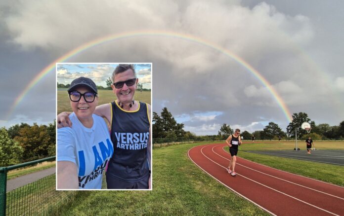 Dave Pettitt running on the Crowborough running track with rainbow in the sky