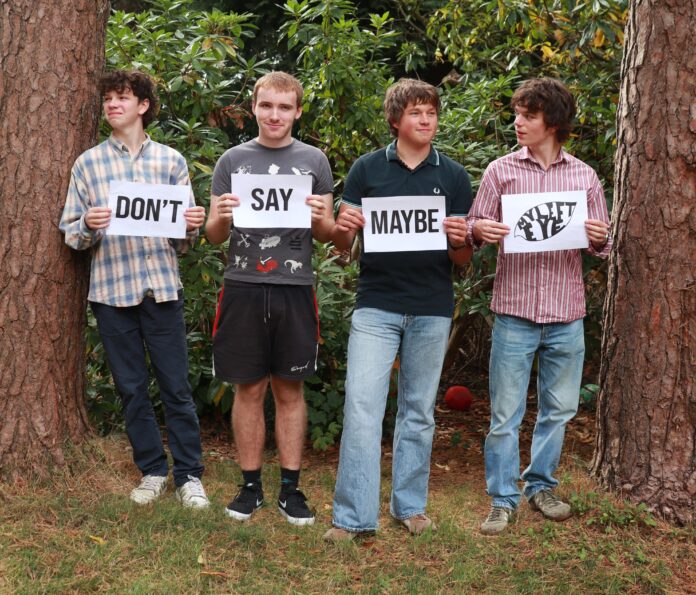 Crowborough band holding cards with the name of their new single - Don't Say Maybe