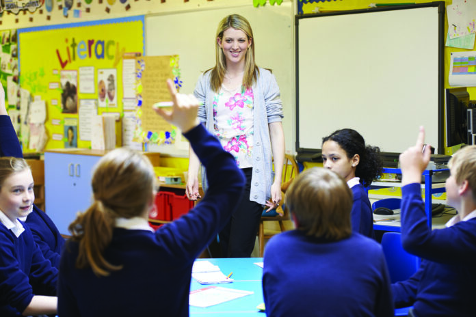 Generic teacher stands in front of class of pupils